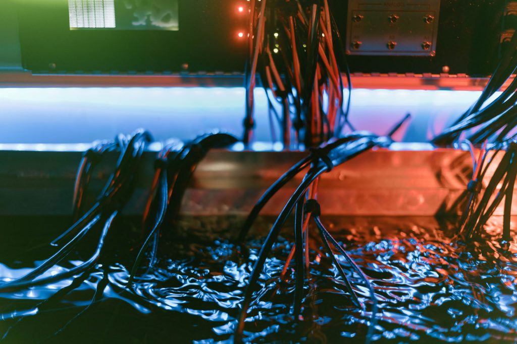Cables descending into liquid cooled container of electronic equipment